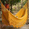 Hamaca artesanal de Morroa color amarillo en jardín Hamaca artesanal de Morroa color amarillo instalada en un jardín con flecos de macramé tejidos a mano