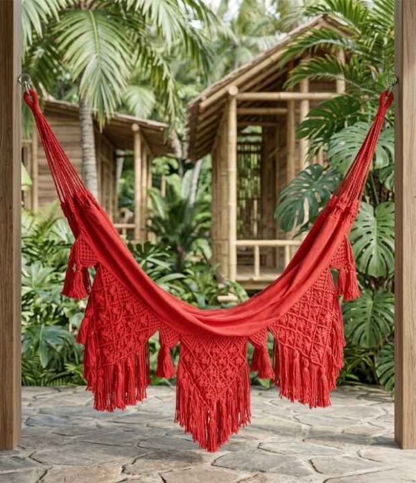 Hamaca de Morroa con macramé color rojo instalada en un jardín tropical