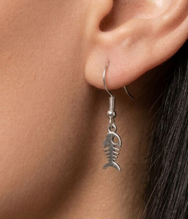 mujer usando aretes esqueleto de pez plateado
