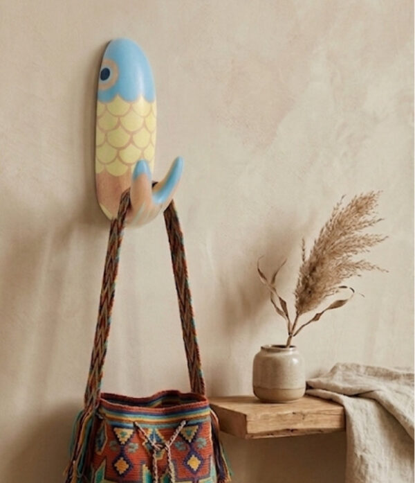 Perchero de pez Escamas en ambiente decorativo Perchero artesanal de pez con diseño Escamas usado como perchero decorativo para colgar un bolso tejido en una pared interior.