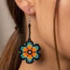 Modelo usando aretes de chaquiras Kamentsa en color azul turquesa y naranja.