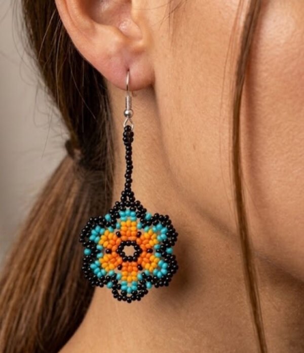 Modelo usando aretes de chaquiras Kamentsa en color azul turquesa y naranja.