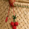 Charm artesanal de cereza decorando un bolso Charm para bolso de fruta en palma de iraca colocado en un bolso tejido