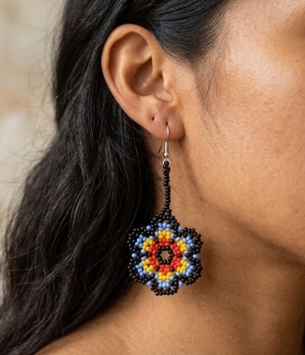 Modelo luciendo aretes de chaquiras Kamentsa en forma de flor multicolor tejida a mano.