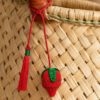 Charm artesanal de fresa decorando un bolso Charm para bolso de fruta en palma de iraca colocado en un bolso tejido