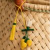 Charm artesanal de limón decorando un bolso Charm para bolso de fruta en palma de iraca colocado en un bolso tejido