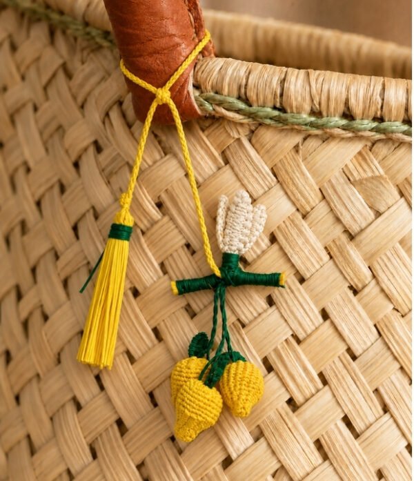 Charm artesanal de limón decorando un bolso Charm para bolso de fruta en palma de iraca colocado en un bolso tejido