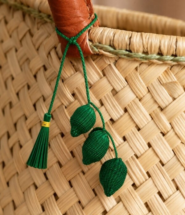Charm artesanal de limones decorando un bolso Charm para bolso de fruta en palma de iraca colocado en un bolso tejido