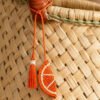Charm artesanal de naranja decorando un bolso Charm para bolso de fruta en palma de iraca colocado en un bolso tejido