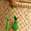 Charm artesanal de pera decorando un bolso Charm para bolso de fruta en palma de iraca colocado en un bolso tejido