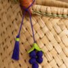 Charm artesanal de uvas decorando un bolso Charm para bolso de fruta en palma de iraca colocado en un bolso tejido