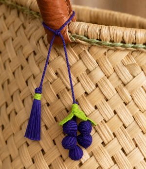 Charm para bolso de fruta en palma de iraca colocado en un bolso tejido